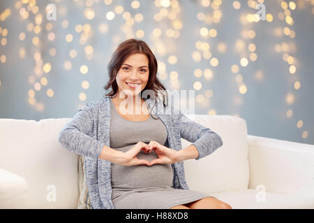happy pregnant woman making heart gesture at home Stock Photo