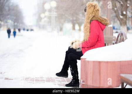 Lonely woman sitting on the bench in park in wintertime Stock Photo