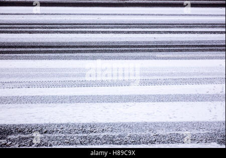 background texture of asphalt road covered with snow and tire tracks Stock Photo