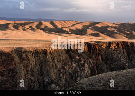Sunset on rolling hills of Black Canyon on the Charyn river with Tien Shen mountains Kazakhstan Stock Photo