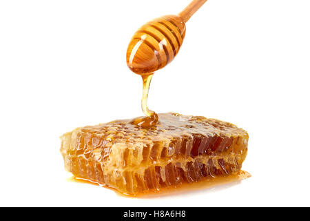 Honey dripping on honeycomb over white background Stock Photo