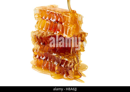 Dripping honey on honeycombs over white background Stock Photo