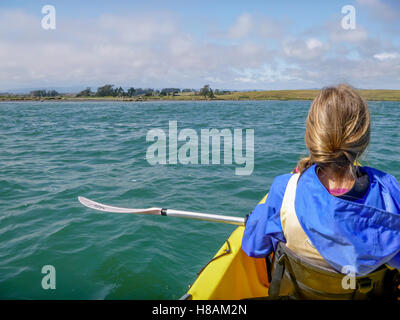 Young woman or girl in yellow kayak on Elkhorn Slough Marine Preserve, Moss Landing, Monterey County,perspective of water, shore Stock Photo