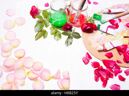 Paints and brushes with rose petals.Workplace of artist,designer.Concept art, creative.Top view background. Stock Photo