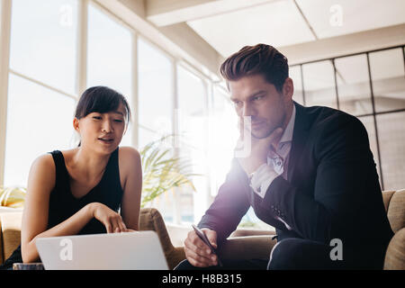 Shot of young businesspeople working on laptop in office. Business partners discussing new project on laptop. Stock Photo