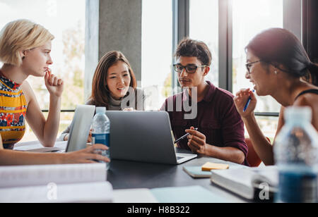 Multiracial young people doing group study at table. University students sitting together at table with books and laptop for res Stock Photo