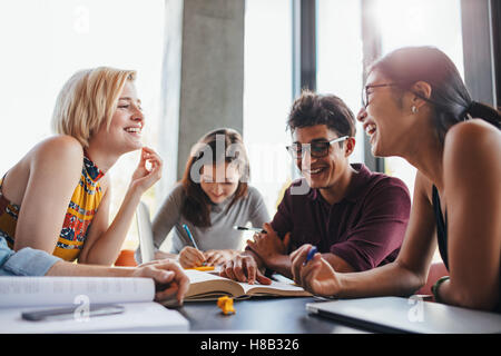 Multiethnic young people sitting at table reading reference books for study notes. Group of happy young students in cooperation Stock Photo