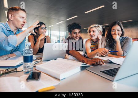 University students using laptop in a library. Students working together on academic project finding information on internet. Stock Photo
