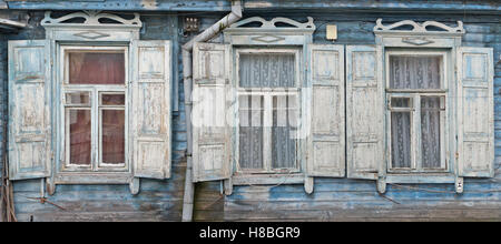 Three windows with an open sun blinds  in the old destroyed blue wooden retro house. Panoramic collage from several photos Stock Photo
