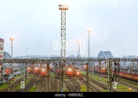 Old locomotives stand on railroad tracks of technical railway station - operational locomotive depot on autumn morning in fog Stock Photo