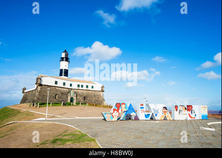 SALVADOR, BRAZIL - FEBRUARY 02, 2016: Colorful sign stands in front of the colonial Farol da Barra lighthouse. Stock Photo