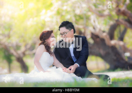Portrait of cheerful wedding couple hugging and looking at the camera. Asian wedding couple in garden Stock Photo