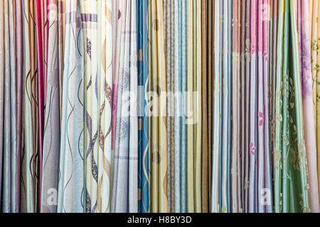 Colorful curtain samples hanging from hangers on a rail in a display in a retail store Stock Photo