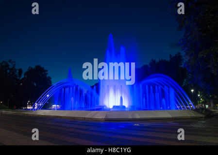 A  water fountain illuminated with blue lights at night Stock Photo