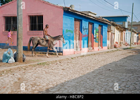 A Cuban man rides a horse bareback through the backstreets of Trinidad Cuba Stock Photo