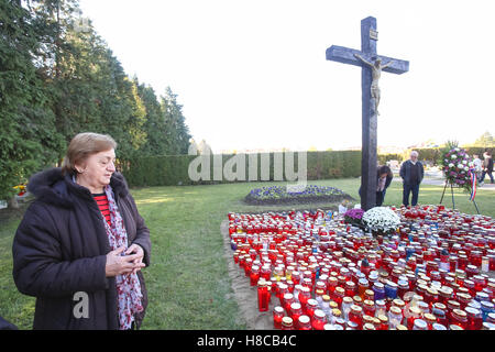 A woman praying in front of the cross with a group of lampions on the ground on All Saints day in Velika Gorica, Croatia. Stock Photo