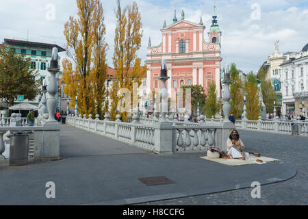 Indian man sat on rug, singing and playing Iktara (or ektara) - single string instrument, at Triple Bridge, Ljubljanica River, L Stock Photo