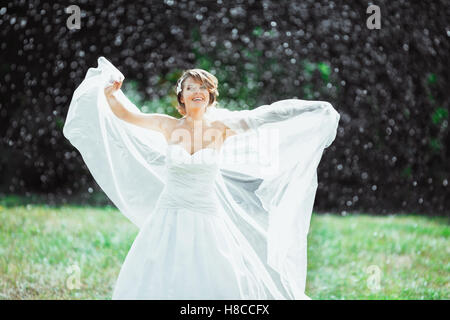Smiling bride standing under rain Stock Photo