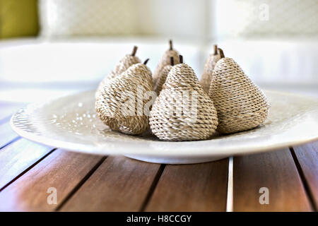 Closeup of a gift item decoration made by a thick thread spun around a wooden stick on a white ceramic plate, colorful room. Stock Photo