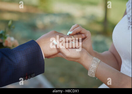 bride wears a wedding ring on the finger of groom Stock Photo
