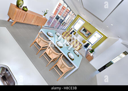 Six carved wooden chairs and light blue classic table ready with dishes on leaf shape design items and wine glasses near three c Stock Photo