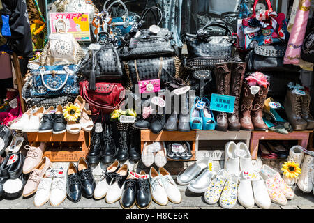 Japan, Tokyo, Harajuku, Takeshita-dori. Hand Bags, boots and shoes displayed on the pavement outside trendy teenage fashion store. Stock Photo