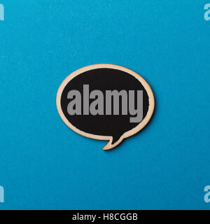 black handcrafted wooden blank speech bubble on blue background Stock Photo