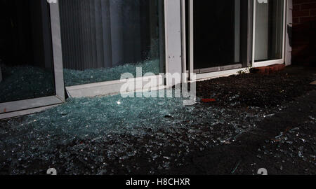 Broken glass and brick pieces on the ground after a burglary Stock Photo