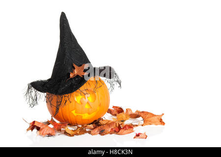 Jack O Lantern sitting on autumn leaves wearing a witches hat Stock Photo