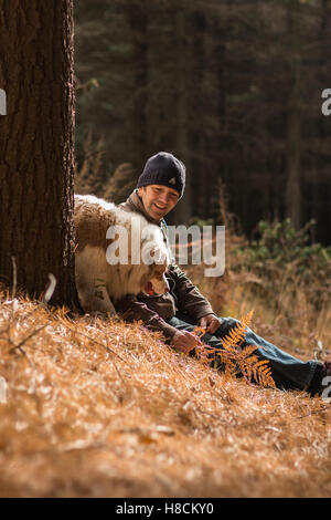 Man and dog enjoying the outdoors together hiking looking happy having fun in the woods amongst nature in autumn colours fall Stock Photo