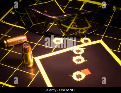 Bullet holes in a target with ammunition and shooting glasses Stock Photo