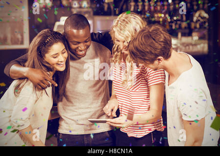 Composite image of happy friends looking at smartphone Stock Photo