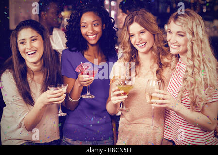 Composite image of friends drinking cocktails together while standing together Stock Photo