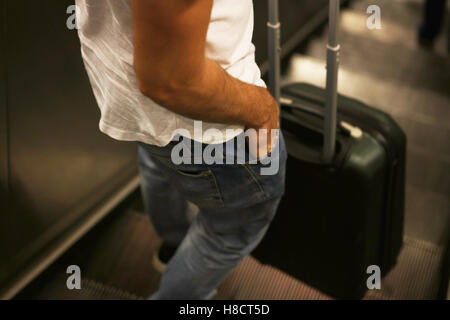 young man going down escalator with travel bag suitcase Stock Photo