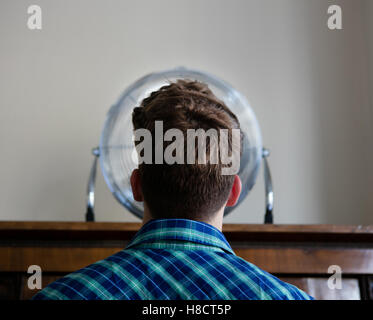 Back of young mans head looking into electric fan Stock Photo