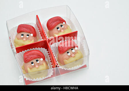 four faces of Santa Claus with hat, pralines in a box on white background, close up, macro, space for text, horizontal Stock Photo