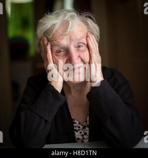 Russian grandmother. Portrait of an elderly woman sitting at a table in his house. Stock Photo