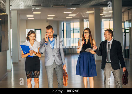 four colleagues go around the office and communicate Stock Photo