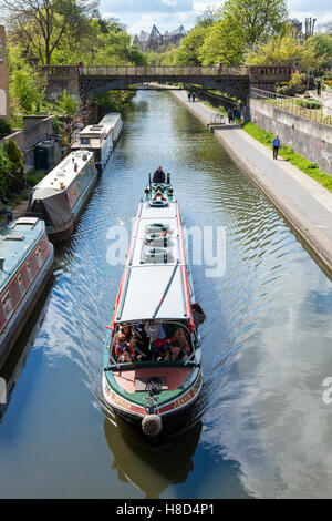 Tourists on a canal boat trip passing moored narrowboats on Regent's Canal, London, England, UK Stock Photo