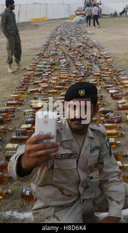 Lahore, Pakistan. 10th Nov, 2016. Pakistani paramilitary soldiers, anti-narcotics force (ANF) and students check the seized wine before crashing and burning them.Pakistani authorities torched tonnes of seized drugs like heroin, hashish, cocaine, liquor and opium during an annual drug burning ceremony attended by anti-narcotics and other officials.P akistan annually seizes huge quantities of drugs which straddle a route from neighboring Afghanistan, destined for lucrative markets in the Middle East. Credit:  Rana Sajid Hussain/Pacific Press/Alamy Live News Stock Photo