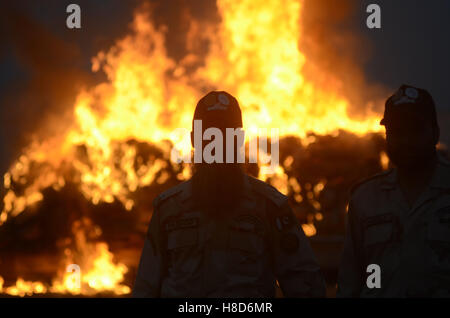 Lahore, Pakistan. 10th Nov, 2016. Pakistani paramilitary soldiers, anti-narcotics Control Forces (ANF) burn a pile of seized drugs smashed bottles liquor. Pakistani authorities torched tonnes of seized drugs like heroin, hashish, cocaine, liquor and opium during an annual drug burning ceremony attended by anti-narcotics and other officials. Pakistan annually seizes huge quantities of drugs which straddle a route from neighboring Afghanistan, destined for lucrative markets in the Middle East. Credit:  Rana Sajid Hussain/Pacific Press/Alamy Live News Stock Photo