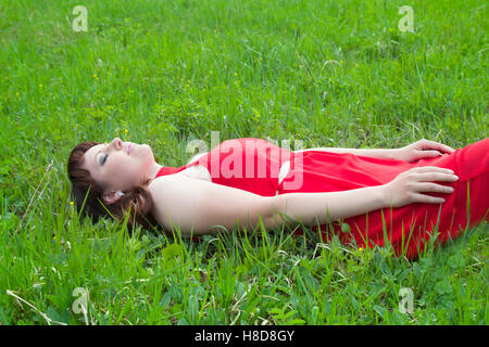 leisure and people concept - young girl in red lying on grass Stock Photo