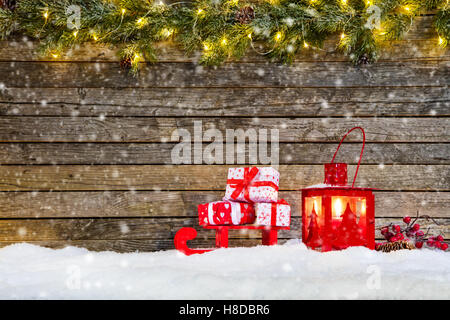 Christmas background with pile of gifts placed on wooden sledge in snow. Fir decoration branches on top Stock Photo
