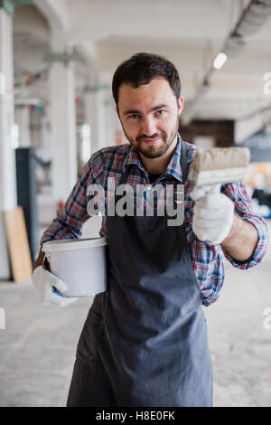 Happy young painter holding paint brush and showing it to camera Stock Photo