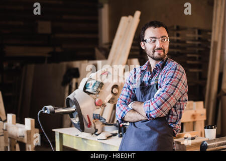 Happy young handyman carpenter in workshop, smiling Stock Photo