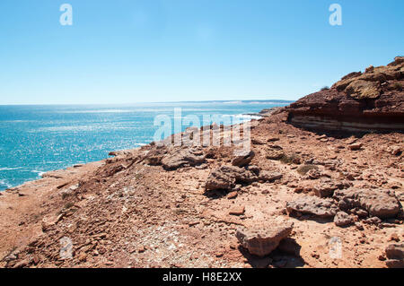 Rugged red sandstone rock and the turquoise Indian Ocean on the coral coast at Pot Alley in Kalbarri, Western Australia. Stock Photo