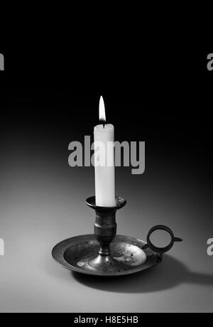 A single burning candle flame or light is glowing on a white spiral ...