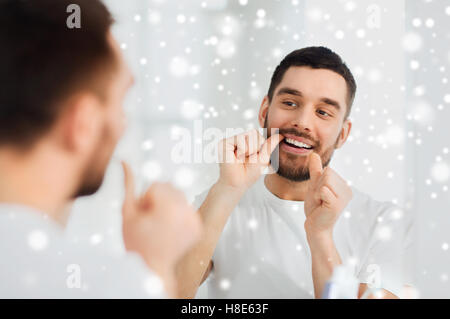 man with dental floss cleaning teeth at bathroom Stock Photo