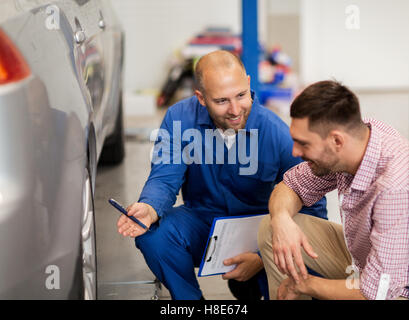 auto mechanic with clipboard and man at car shop Stock Photo