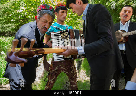 Group of traditional musicians with accordion durinin Khorog,  Pamir  - GBAO province in Tajikistan. Man wears typical hat of ishkashim, GBAO province Stock Photo
